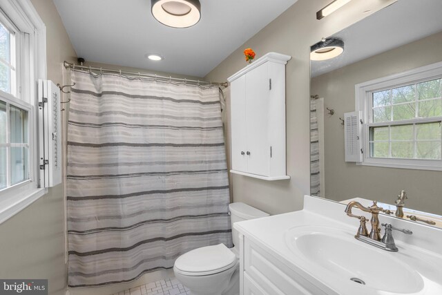 bathroom featuring toilet, vanity, and a shower with curtain