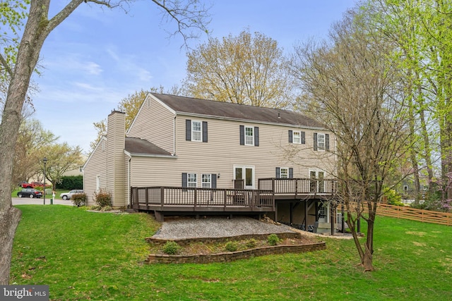 rear view of property with a yard, fence, a deck, and a chimney