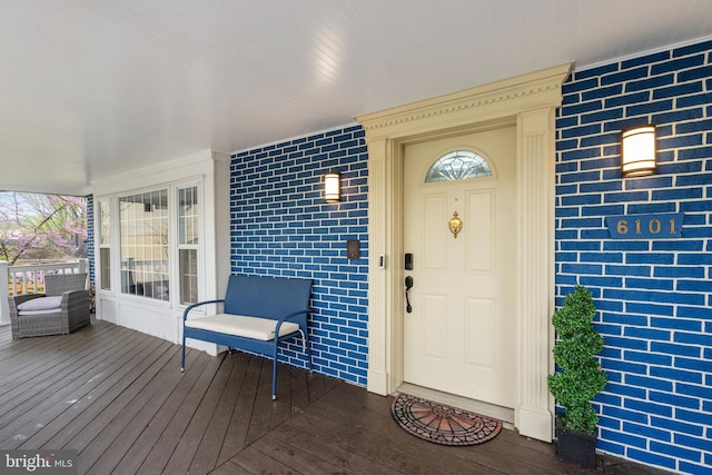 doorway to property with a porch and brick siding