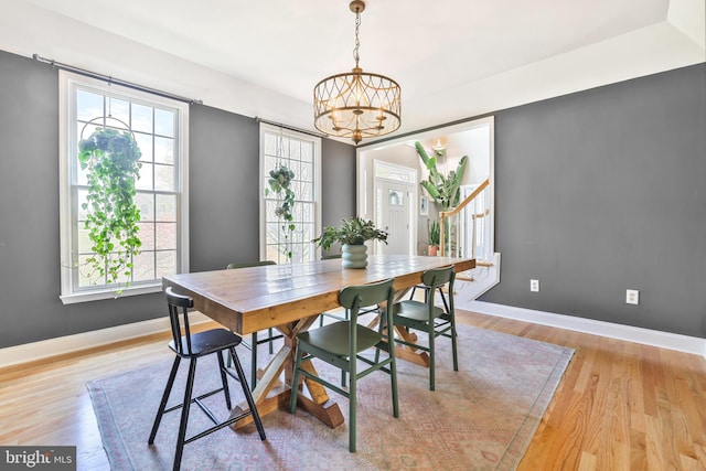 dining space with light wood-style floors, plenty of natural light, baseboards, and an inviting chandelier