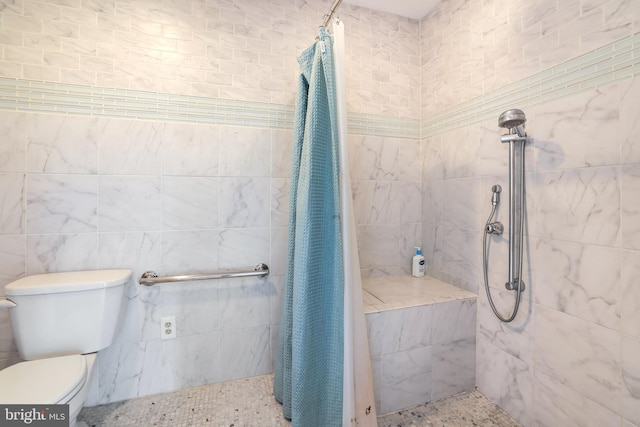 bathroom featuring tile walls, toilet, and a tile shower