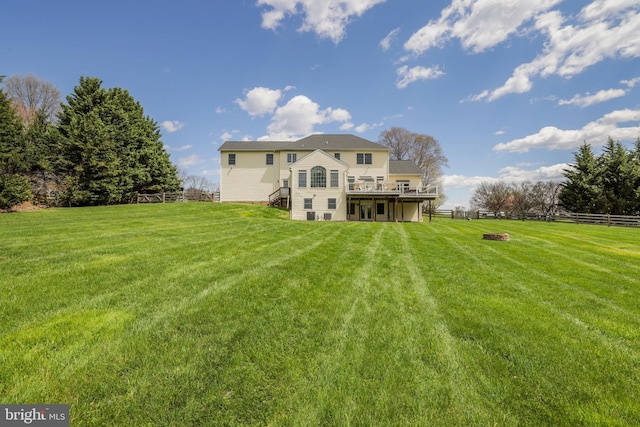 back of house featuring a lawn, a fire pit, stairs, and a deck