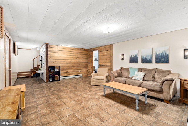 living area with stairway, wooden walls, and a baseboard heating unit