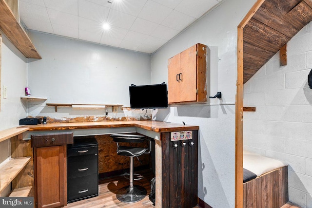 home office with light wood finished floors and concrete block wall