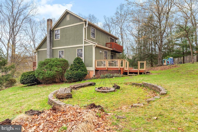 view of side of home featuring an outdoor fire pit, a yard, a wooden deck, and a chimney