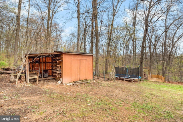 view of shed with a view of trees and a trampoline