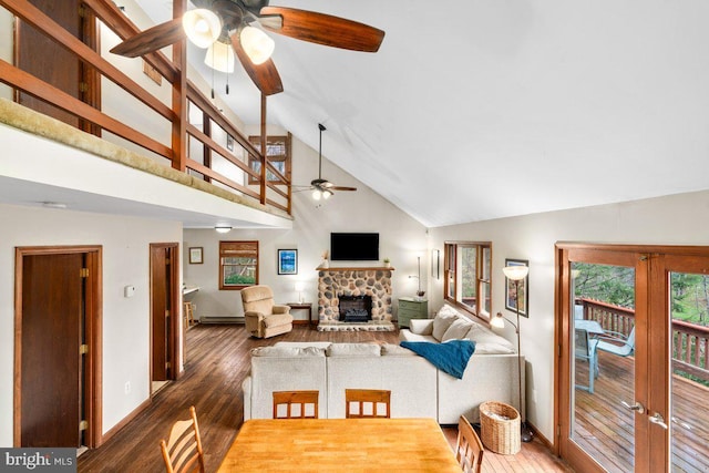 living area with baseboards, a stone fireplace, ceiling fan, wood finished floors, and high vaulted ceiling