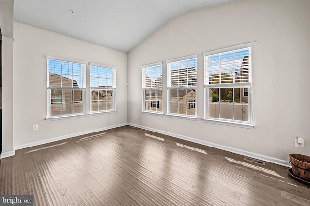 empty room with visible vents, baseboards, vaulted ceiling, and wood finished floors