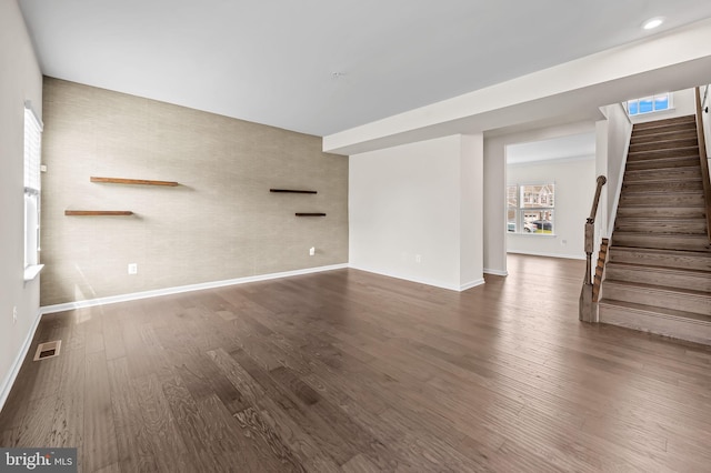 unfurnished living room with stairs, dark wood-type flooring, visible vents, and baseboards