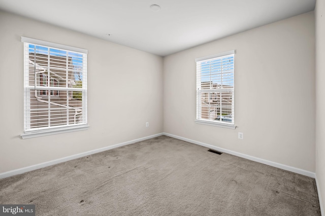carpeted empty room with visible vents and baseboards