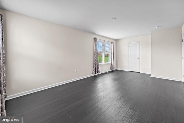 empty room with dark wood-style flooring and baseboards