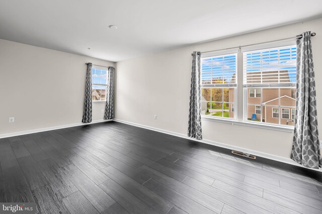 spare room featuring dark wood-style floors, baseboards, and visible vents