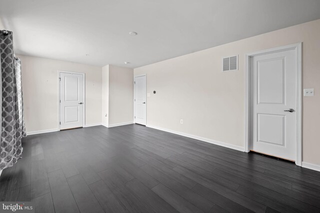 unfurnished living room featuring visible vents, baseboards, and dark wood-style floors