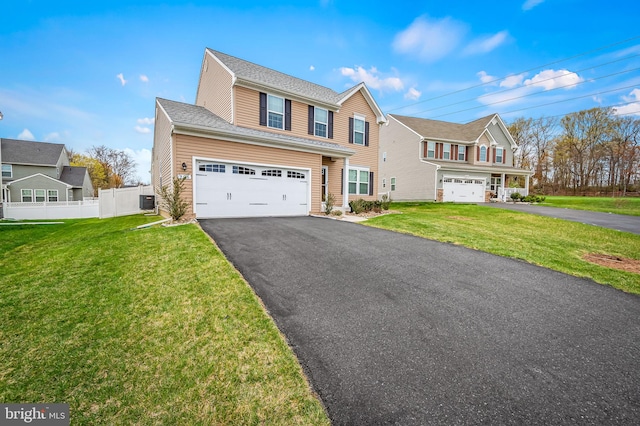 traditional home featuring an attached garage, fence, driveway, and a front lawn