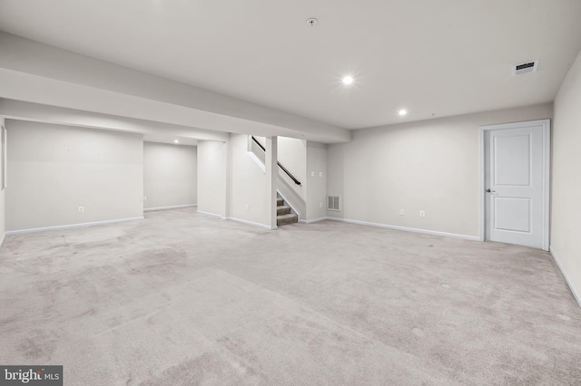 finished below grade area featuring light colored carpet, recessed lighting, visible vents, and stairway