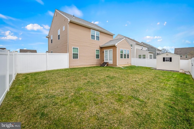 back of property featuring a storage shed, a fenced backyard, an outdoor structure, a lawn, and entry steps