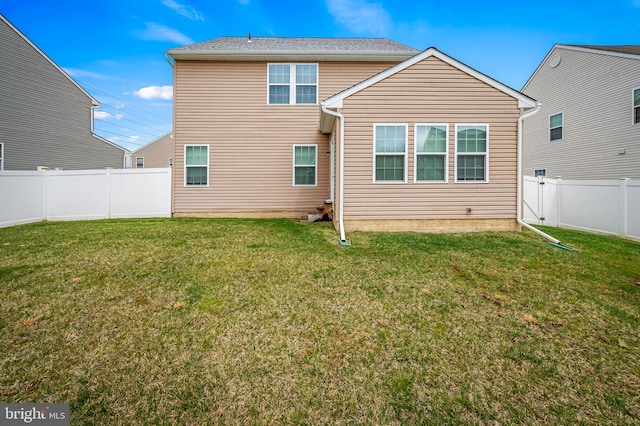 rear view of house with a fenced backyard and a lawn