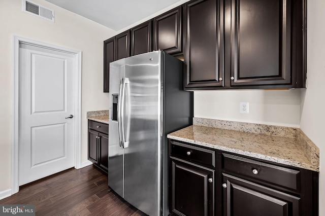 kitchen with stainless steel fridge with ice dispenser, visible vents, light stone countertops, and dark wood-style flooring