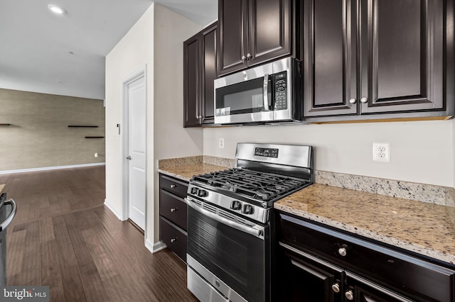 kitchen with baseboards, appliances with stainless steel finishes, light stone counters, and dark wood finished floors