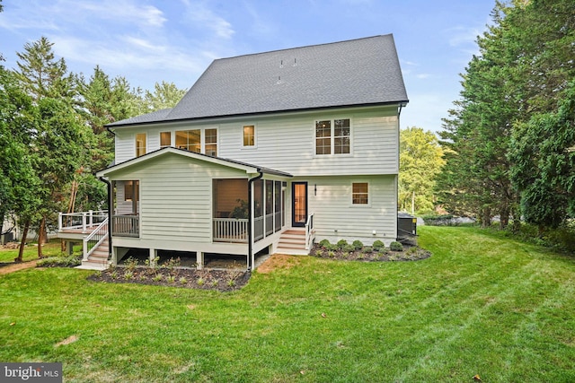 rear view of house featuring a lawn, a sunroom, and roof with shingles