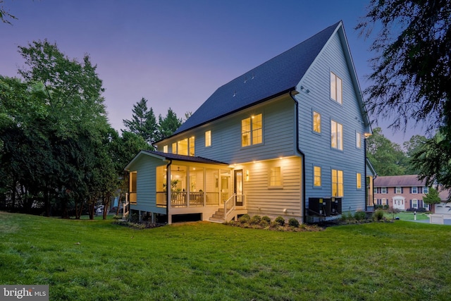 back of house at dusk featuring a lawn