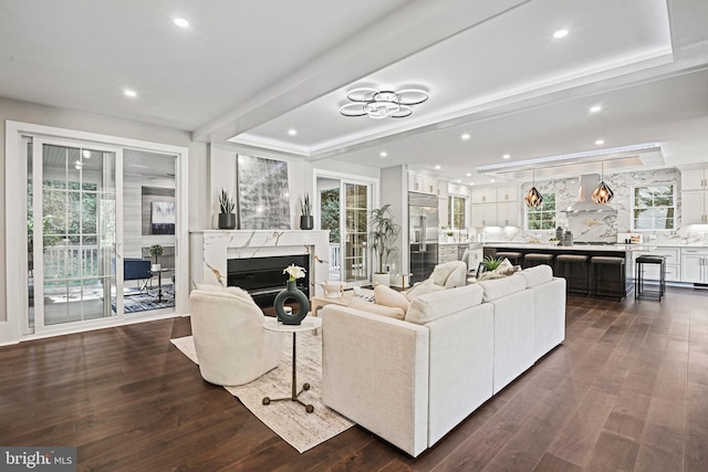living area featuring a tray ceiling, a fireplace, recessed lighting, and dark wood finished floors
