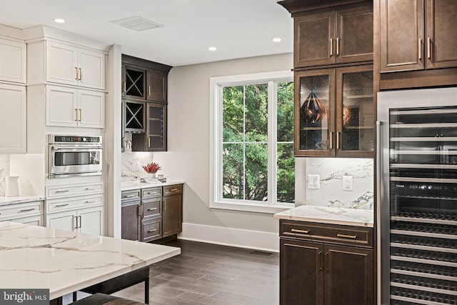 kitchen featuring stainless steel oven, baseboards, light stone counters, and beverage cooler