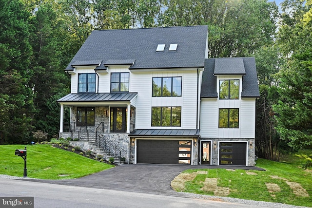 view of front of property with a standing seam roof, stone siding, an attached garage, a shingled roof, and a front yard