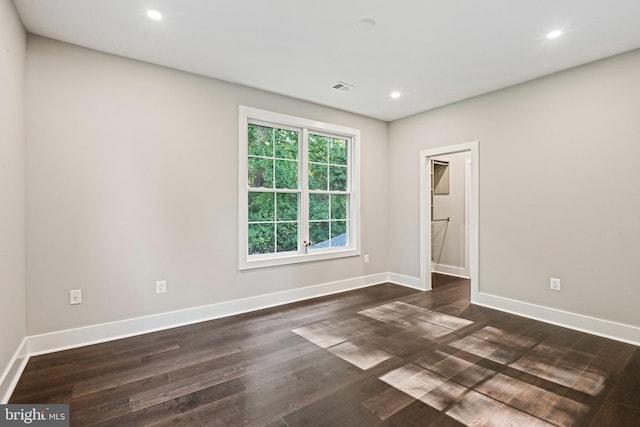 spare room featuring baseboards, dark wood-type flooring, visible vents, and recessed lighting