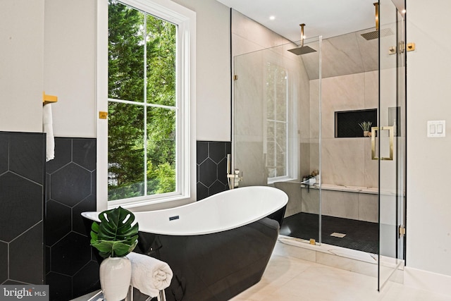 bathroom featuring a shower stall, a soaking tub, visible vents, and tile walls