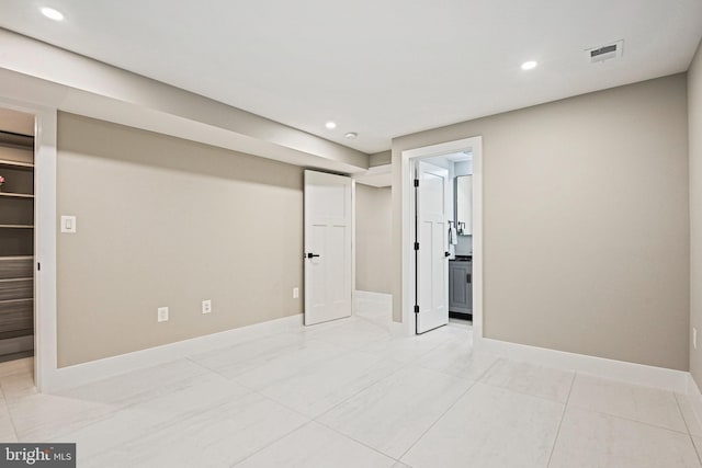 unfurnished bedroom featuring a spacious closet, connected bathroom, baseboards, visible vents, and recessed lighting