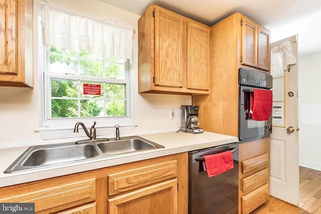 24171 Adelaide St, Parksley, VA 23421 - kitchen featuring light countertops, a sink, dishwashing machine, light wood-style flooring, and black oven