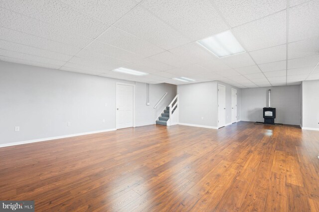 15920 Broadfording Rd, Hagerstown, MD 21740 - unfurnished living room with wood-type flooring, stairway, a wood stove, baseboards, and a paneled ceiling