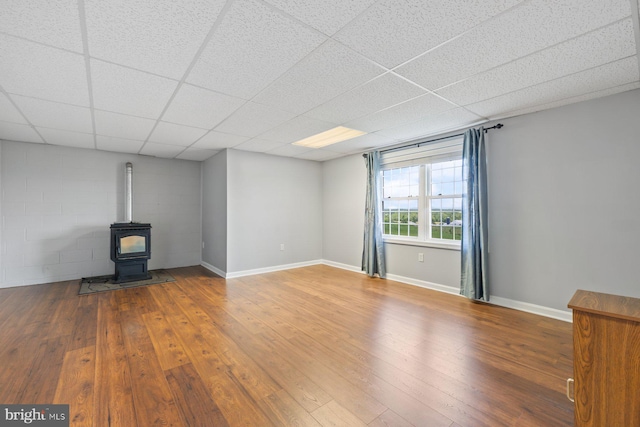 15920 Broadfording Rd, Hagerstown, MD 21740 - unfurnished living room with hardwood / wood-style floors, a paneled ceiling, a wood stove, concrete block wall, and baseboards