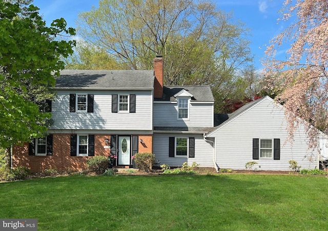 view of front of house featuring brick siding, a front lawn, and a chimney