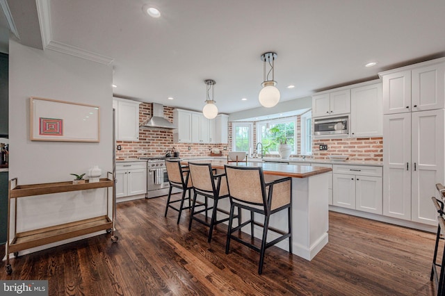 312 Center Hill Rd, Wilmington, DE 19807 - kitchen featuring white cabinets, appliances with stainless steel finishes, wall chimney exhaust hood, and a kitchen bar