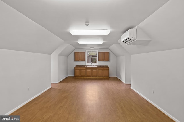 additional living space featuring baseboards, a wall unit AC, wood finished floors, and lofted ceiling