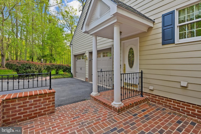 entrance to property featuring an attached garage and aphalt driveway