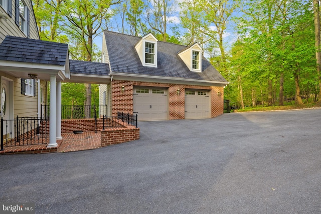 view of side of home with brick siding, a garage, and driveway