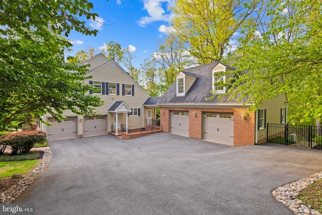 view of front facade with fence, a garage, driveway, and brick siding