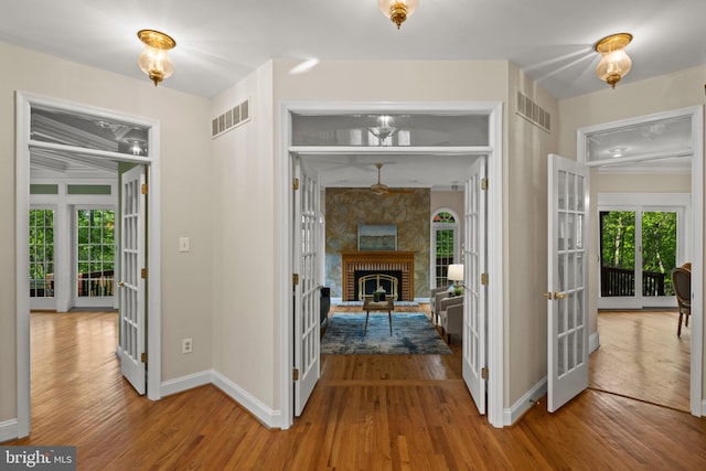 hallway featuring visible vents, baseboards, wood finished floors, and french doors