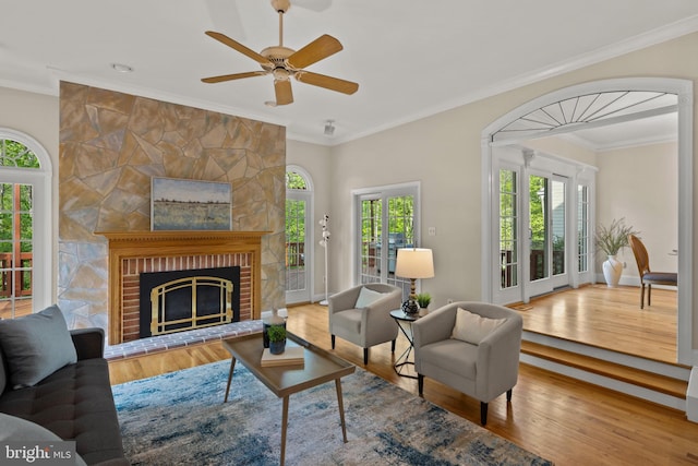 living room with ceiling fan, ornamental molding, wood finished floors, and a fireplace
