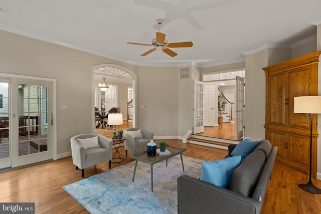living area featuring a ceiling fan, ornamental molding, a healthy amount of sunlight, and light wood finished floors