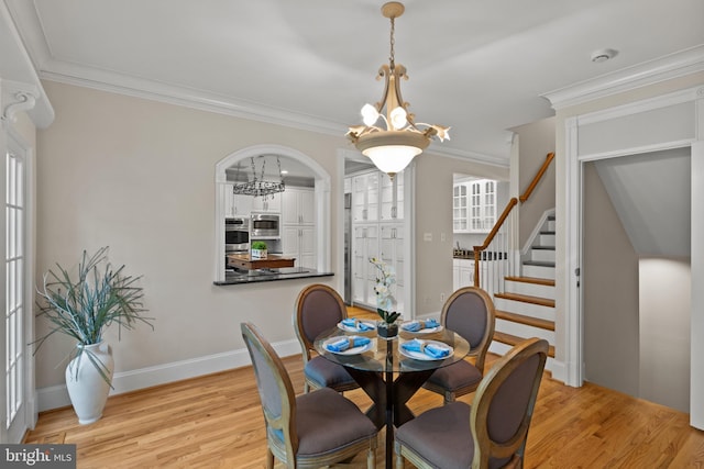 dining space featuring crown molding, stairs, light wood-style flooring, and a chandelier