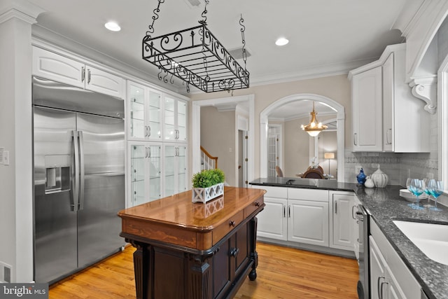 kitchen with ornamental molding, recessed lighting, white cabinetry, arched walkways, and stainless steel appliances