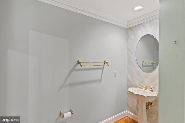 bathroom with baseboards, ornamental molding, and wood finished floors