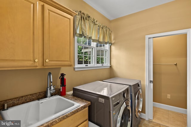 washroom with cabinet space, baseboards, a sink, and washer and dryer