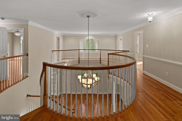 hall featuring crown molding, an upstairs landing, wood finished floors, baseboards, and a chandelier
