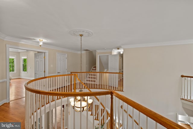 corridor featuring crown molding, stairs, baseboards, an upstairs landing, and light wood-type flooring