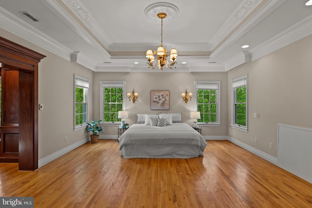 bedroom featuring a tray ceiling, a notable chandelier, multiple windows, and light wood-style flooring